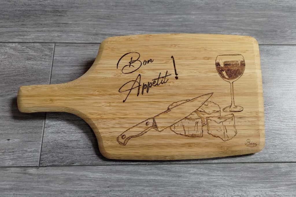 Planche apéritive avec dessin verre de vin, fromage et couteau. Ecriture Bon appétit